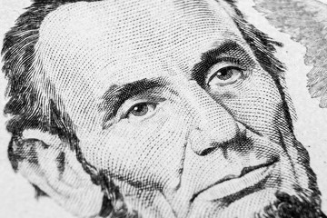Close up view Portrait of Abraham Lincoln on the one five dollar bill. Background of the money. 5 dollar bill with Abraham Lincoln eyes macro shot. Money background. Face portrait. Black and white