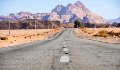 (selective focus) Kings highway, beautiful road running through the Wadi Rum desert with rocky mountains in the distance, Jordan.