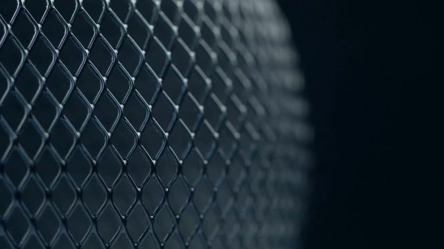 Black metal grid rotating on dark background. Close up macro 4k footage.