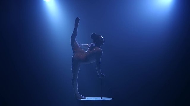 Gymnast performs tricks on the table in the studio. Smoke blue background. Slow motion