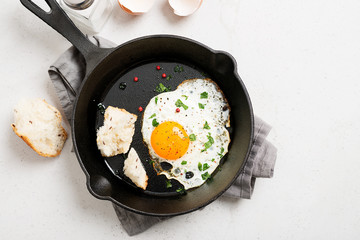Fried egg for delicious healthy easy breakfast on a table. Fresh homemade meal on a frying pan.