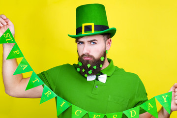 Happy young adult man male in green shirt, green leprechaun hat and tie bow with lucky clover...