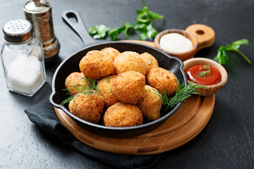 Potato croquettes - mashed potatoes balls breaded and deep fried, served with different sauce.