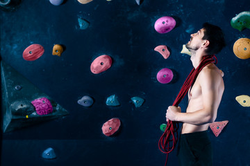 Successful self confident muscle healthy winner climber mountaineer alpinist man male with rope training in climbing wall. Looking at top of wall in bouldering competition. Success healthy lifestyle