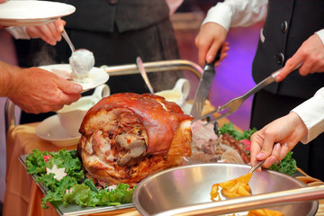 waiter serves roasted meat and baked potatoes at the party or wedding reception