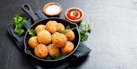 Potato croquettes - mashed potatoes balls breaded and deep fried, served with different sauce.