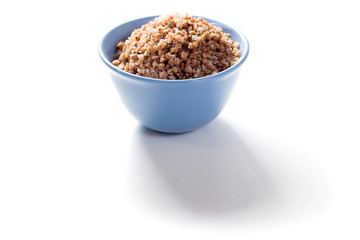 Boiled buckwheat in blue deep plate on white background with shadow