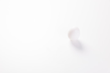 one white egg in with a shadow on a grey background vertically