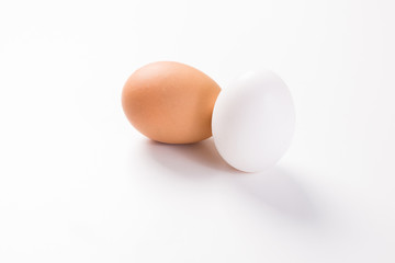 brown and white egg side by side on white background with shadow
