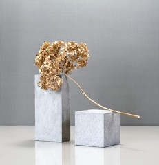 Creative minimalism still life with the use of concrete blocks and a golden plant.