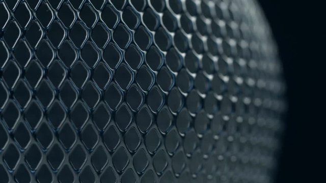 Black metal grid rotating on dark background. Close up macro 4k footage.