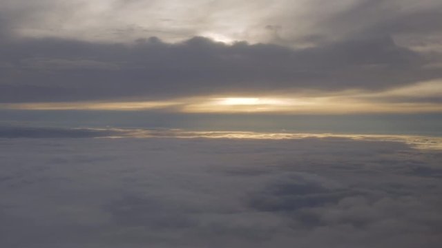Aerial view floating towards the sun setting between the clouds high in the sky