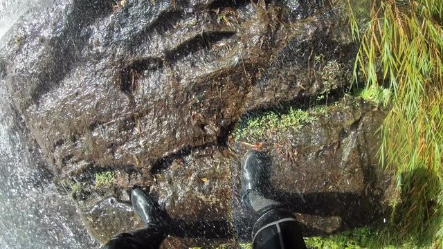 4K, POV Shot of person practice rock climbing down the waterfall. Man climbs rope in deep jungle. Canyoning rappel through waterfalls. Adventurer climber with protection helmet rappel-Dan