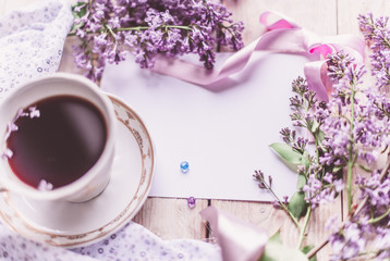 Morning cup of tee, cookies, and lilac flower on wooden table from above. Beautiful breakfast. Flat lay style with copy space