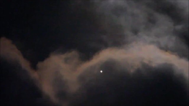 Close up to Jupiter and its moon covered by earth clouds taken with telescope in the dark space.