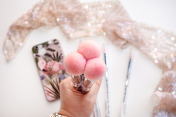 female hand holding three makeup brushes with a pink nap. Concept illustration of beauty and fashion style and makeup articles.