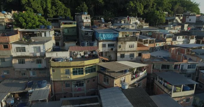 Aerial tracking past sunlit favela houses on hilltop at sunrise in Rio de Janeiro, Brazil