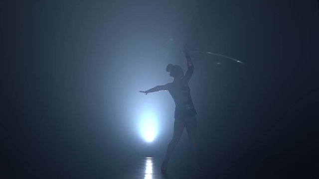 Speech professional gymnast with metal hoops. Slow motion. Smoke background. Silhouette