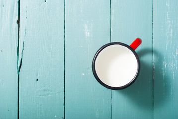 milk in dotted enamel mug, blue wood background