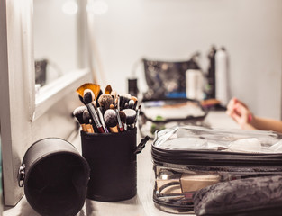 Makeup artist tools-makeup brushes and cosmetic products on the table with a mirror.
