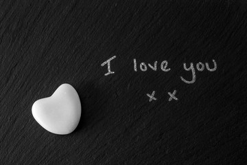 White stone heart on black background with the words I love you.