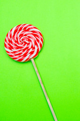 lollipop, a beautiful red and white striped round lollipop on a green background