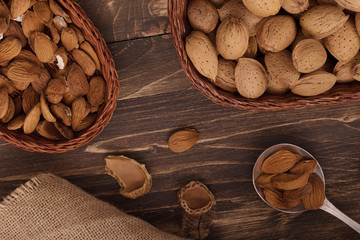 Flat lay of almonds in the wicker plates with other accessories on brown wooden background top view 3
