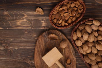 Flat lay of almonds in the wicker plates with other accessories on brown wooden background top view 4