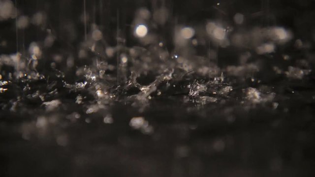 Dreamy splashes of rainy water dazzling on a cave land with strange dots in slo-mo  