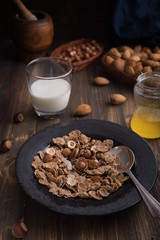 Side view of healthy breakfast with nuts and corn flakes on brown rustic background