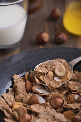 Close up view of healthy breakfast with nuts and corn flakes on brown rustic background