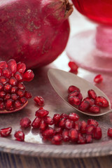 Pomegranate seeds on the spoon with pomegranate juice in a glass on the silver tray close view 3