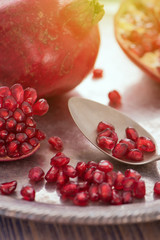 Pomegranate seeds on the spoon with pomegranate juice in a glass on the silver tray close view, toned