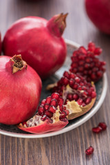 Obraz na płótnie Canvas Pomegranate juice in a glass with fresh pomegranates around with scattered seeds on wooden background