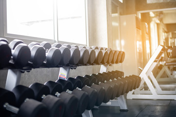 Fototapeta na wymiar Metal dumbbells, flare light in the gym with high contrast with copy space , sport equipment in gym concept
