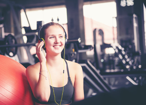 Young sporty fit caucasian woman using smartphone listening music and texting while taking a break in fitness gym .Sport fitness, lifestyle workout and technology for healthy concept
