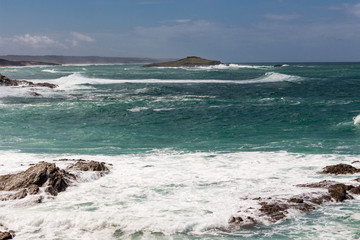 Fototapeta na wymiar Wavy turquoise ocean. Ocean foam. Rocks in the ocean. Nature scenery.