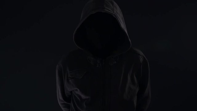 Hooligan with hoodie and obscured face at night looking spooky and threatening