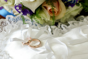 Wedding bouquet with wedding rings. Gold wedding rings lie near the bouquet for the bride. Wedding accessories