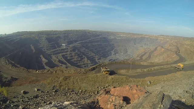 Timelapse quarry. Iron ore mining. Huge quarry on which BelAZ and excavators drive.