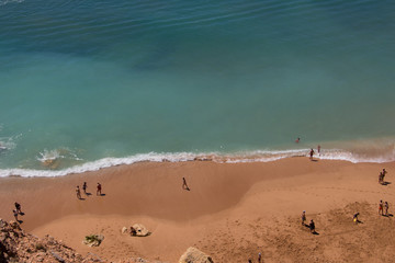 Aerial view of people on a sandy beach on a sunny spring day on the coast, Praia de Benagil, Algarve, Portugal.