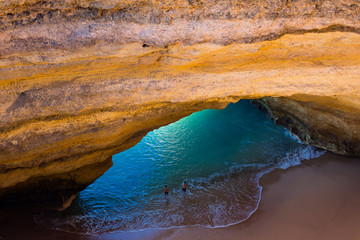 Aerial view of the impressive Benagil sea cave, a coastal sandstone cave. Two men in the water.