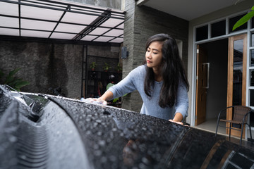 woman cleaning and washing her black car