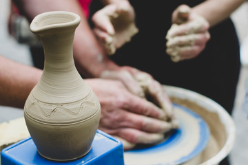 Making it together. Top view of potter teaching child to make ceramic pot on the pottery wheel. pottery workshop