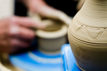 Street master class on modeling of clay on a potter's wheel In the pottery workshop. Focus on the vase, the process of making the vase blurred against the background