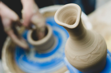 Street master class on modeling of clay on a potter's wheel In the pottery workshop. Focus on the vase, the process of making the vase blurred against the background