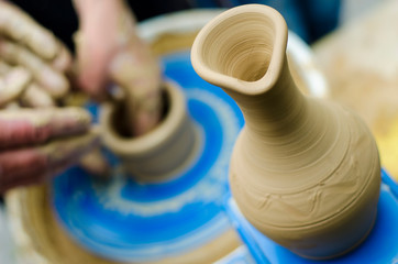 Street master class on modeling of clay on a potter's wheel In the pottery workshop. Focus on the vase, the process of making the vase blurred against the background