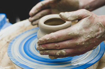 Creating a jar or vase of white clay close-up. Man hands making clay jug macro. The sculptor in the workshop makes a jug out of earthenware closeup. Twisted potter's wheel. Master crock.