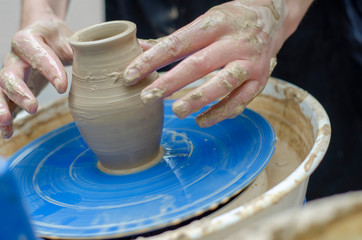 clay pot and hands that created it. Handmade vase making with wet clay and hand potter's wheel In the pottery workshop