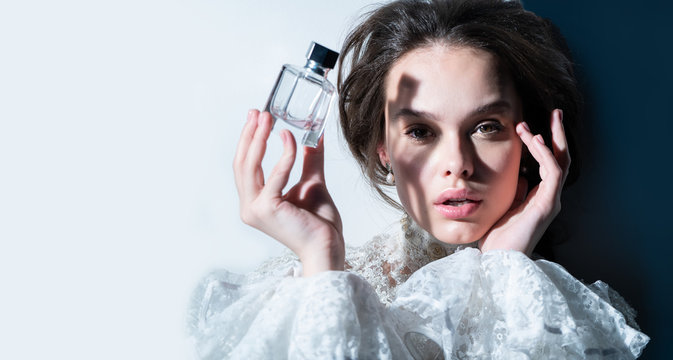 cute girl holding a bottle of perfume in the face